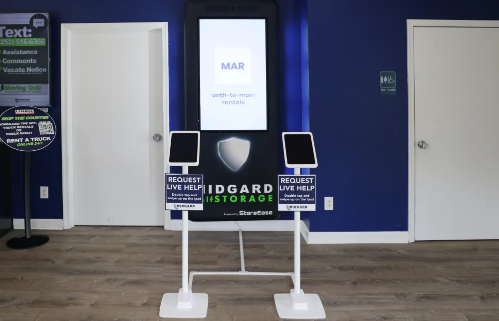 Midgard Storage digital kiosk with live help tablets in a room with blue walls and wooden floor.