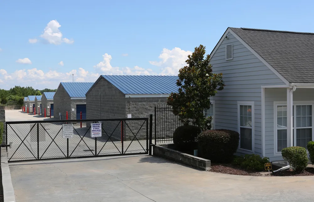 a building with a fence and bushes in front of it