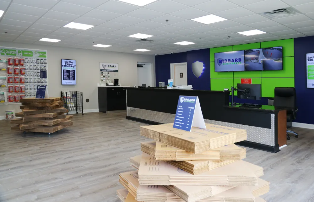 Midgard Self Storage lobby with counter, packaging supplies, and security monitors on a green and blue wall.