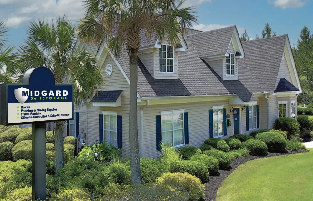 Midgard Self Storage facility with landscaping, palm trees, clear blue sky, and a large sign listing services offered.