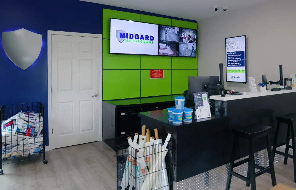 Midgard Self Storage office with green and blue decor, informative monitors, and packing supplies on display.