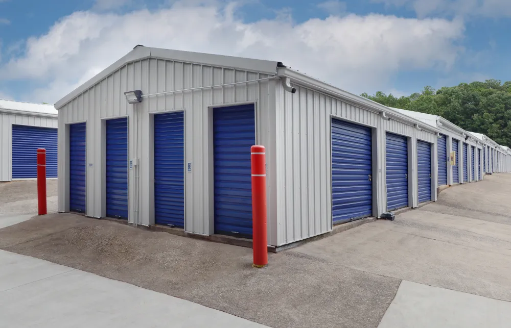 Exterior view of a self-storage facility with multiple blue roll-up doors and a clear sky above.