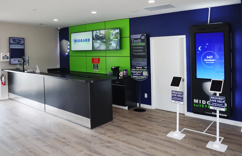 Modern self-storage office interior with sleek black counter, digital screens, and customer service kiosks.
