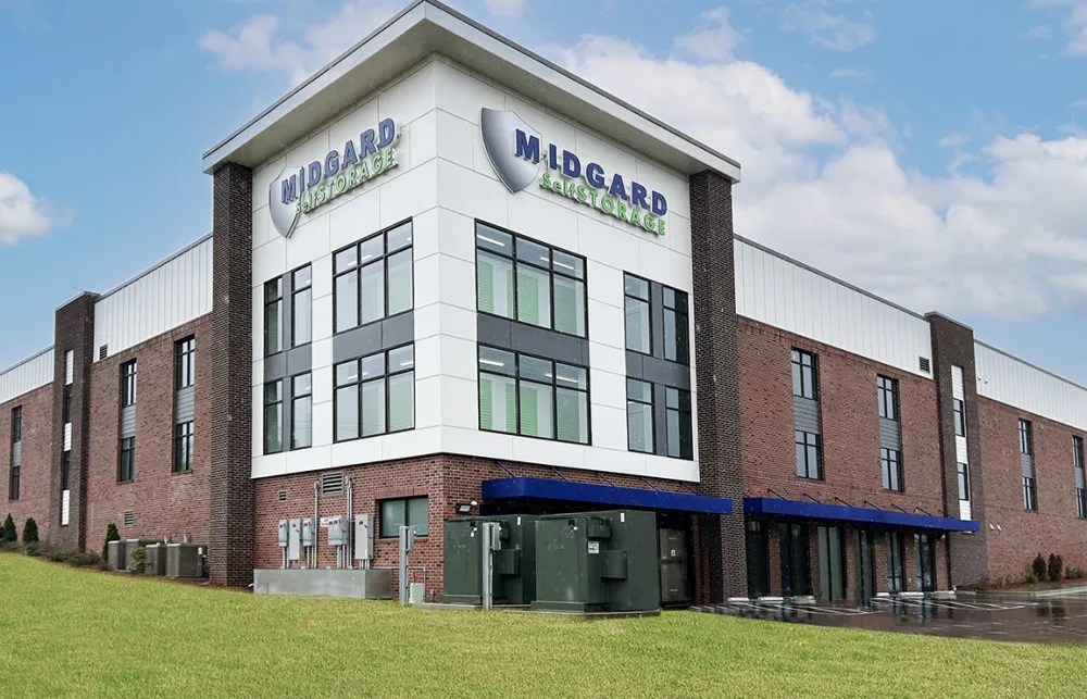 Modern Midgard Self Storage building with brick and white panel exterior under a blue sky with clouds.