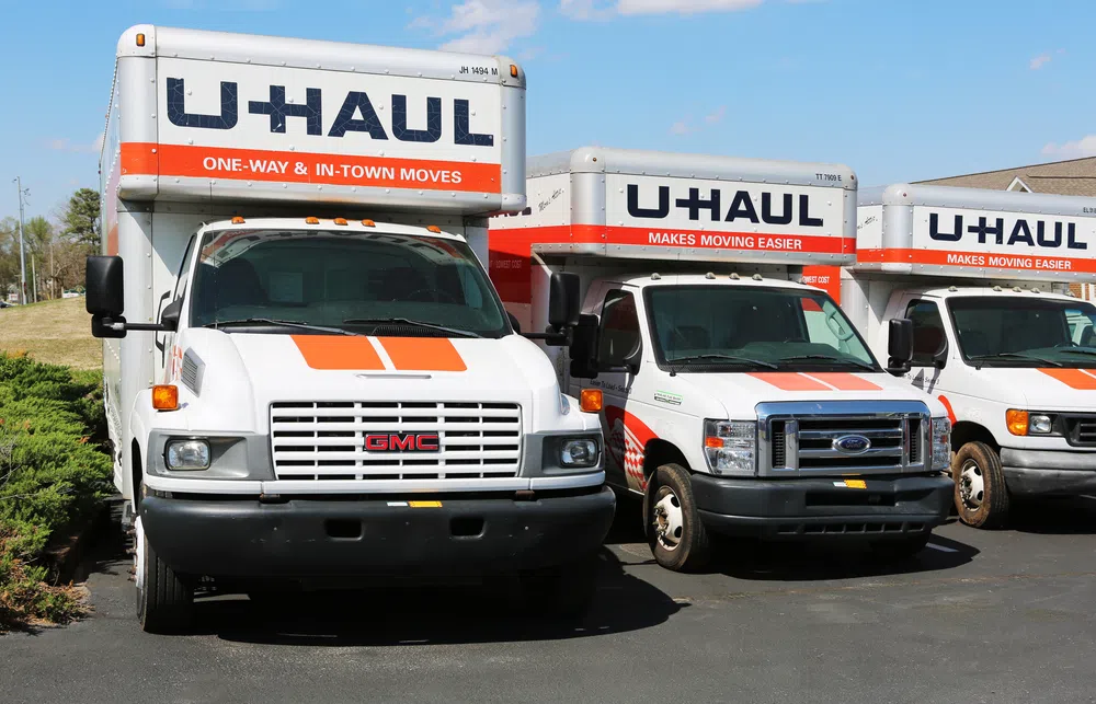 Three U-Haul moving trucks parked side by side under clear blue sky with branding and orange accents