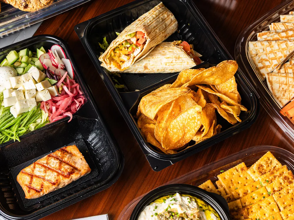 Spicy chicken wings with ranch dip, carrot sticks, celery, grilled flatbreads, and loaded nachos in trays.