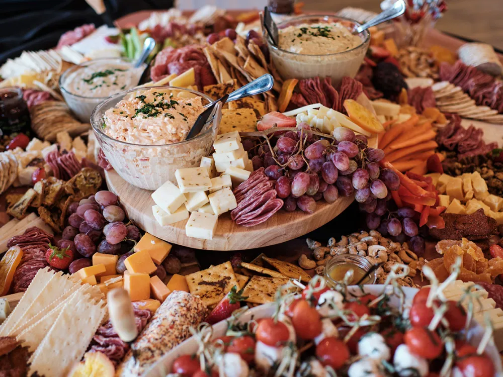 Three diverse friends happily toasting drinks over a table of gourmet food in a cozy restaurant.