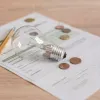 Light bulb and coins on a utility bill representing energy costs and savings.