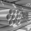 Stacks of white PVC pipes neatly arranged in rows in a warehouse or storage area.