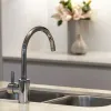Modern stainless steel kitchen faucet over double sink with blurred floral decoration in background