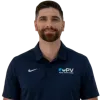 Man in navy polo shirt with PV logo and khaki pants standing with hands in pockets smiling