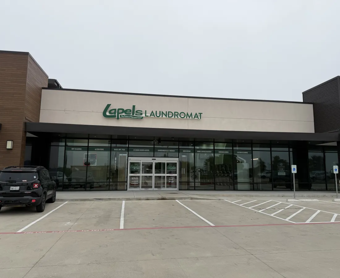 Modern Lapels Laundromat storefront with glass windows and parking area under cloudy sky.