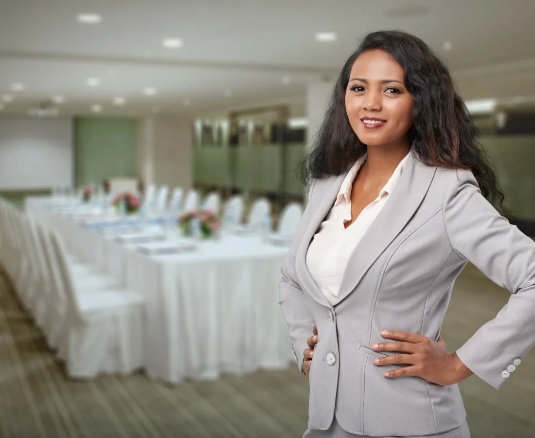 Confident businesswoman in gray suit standing in a modern conference room with a long table and chairs.