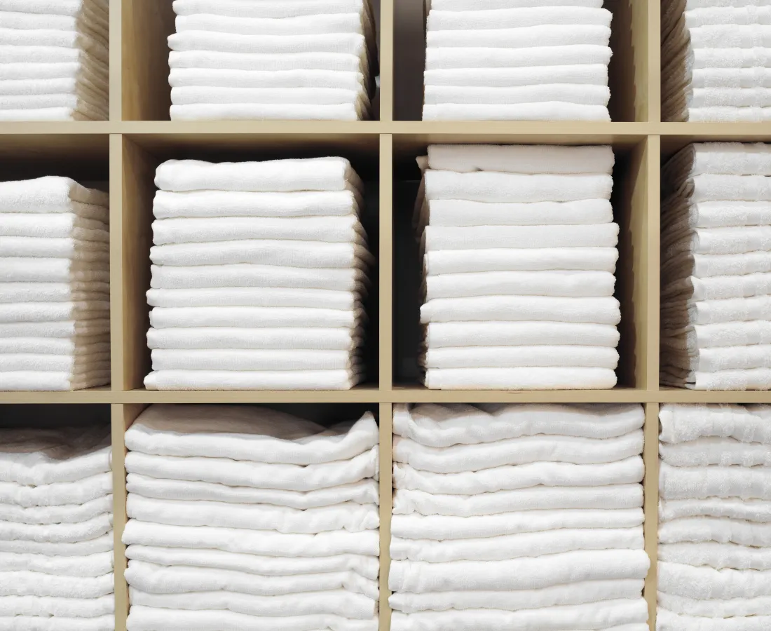 Neatly stacked white towels arranged in wooden cubby shelves creating a clean, organized display.