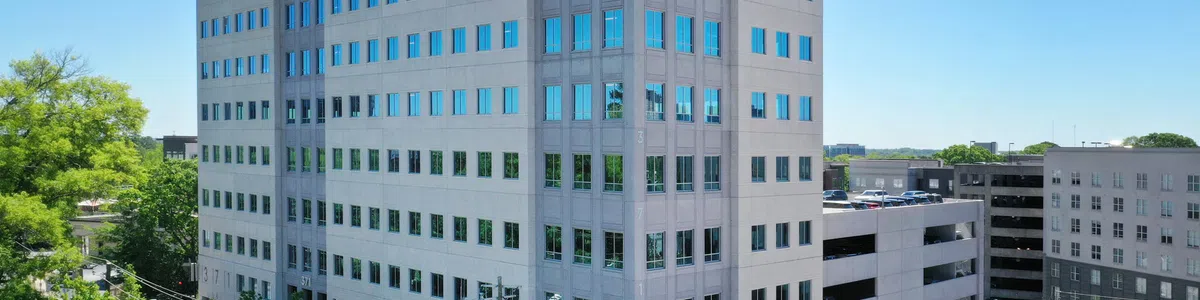 Modern multi-story office building with reflective windows under clear blue sky in an urban environment.