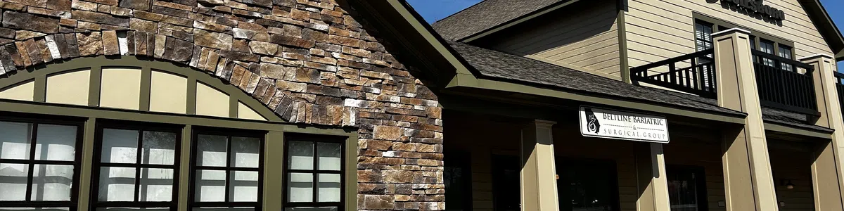 Modern two-story commercial building with stone facade and beige siding under clear blue sky