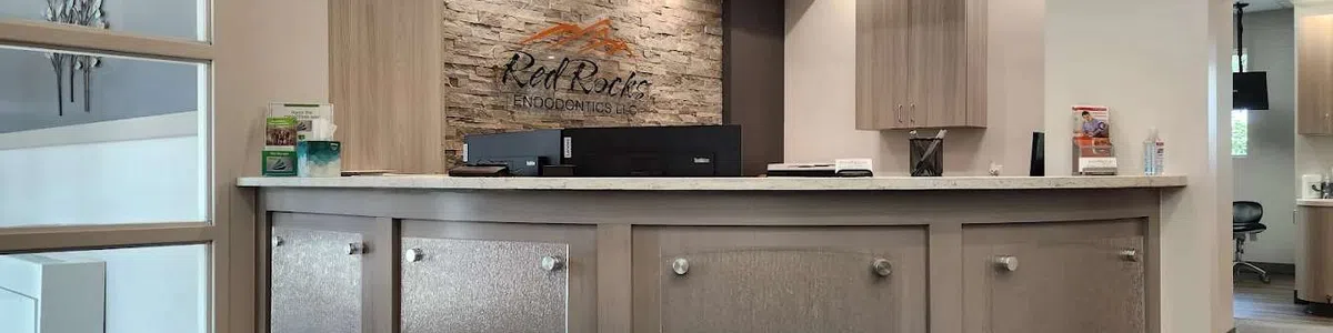 Modern reception area at Red Rocks Endodontics with curved desk, stone accent wall, and soft lighting.