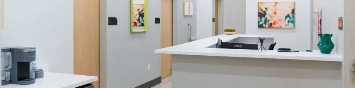 Modern medical office reception area with white walls, wooden doors, and abstract art on the walls.