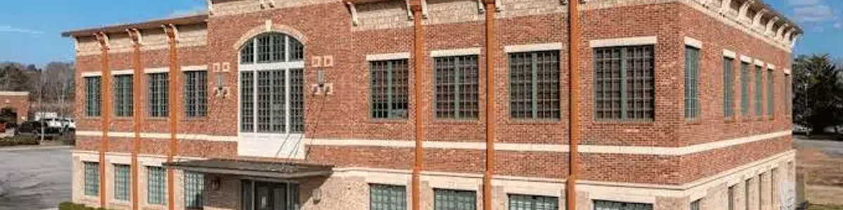 Two-story brick commercial building with large windows under a blue sky and handicapped parking spots in front.
