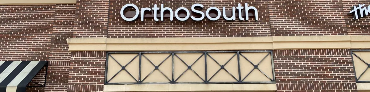 Exterior view of OrthoSouth clinic showcasing brick facade and modern signage.