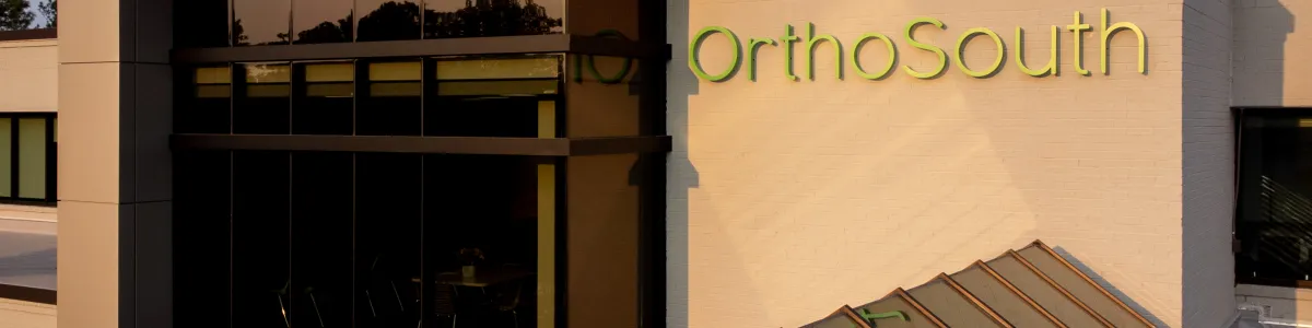 Modern OrthoSouth building with sleek architecture and glass roof during golden hour.