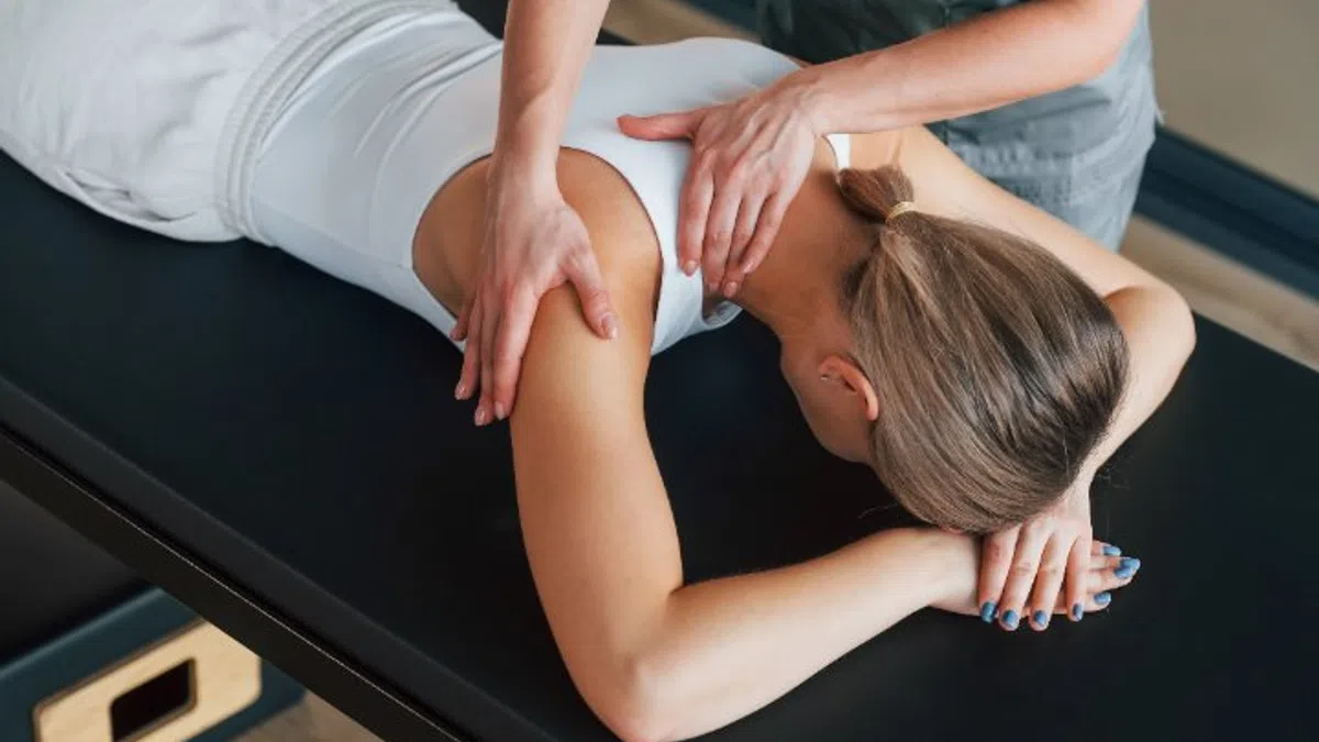 Close-up of a woman receiving a shoulder massage while lying face down on a massage table in a spa.