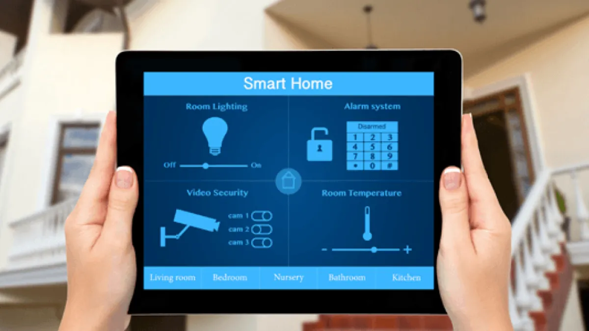 Person holding tablet displaying smart home control panel with lighting, alarm, security cameras, temperature settings.
