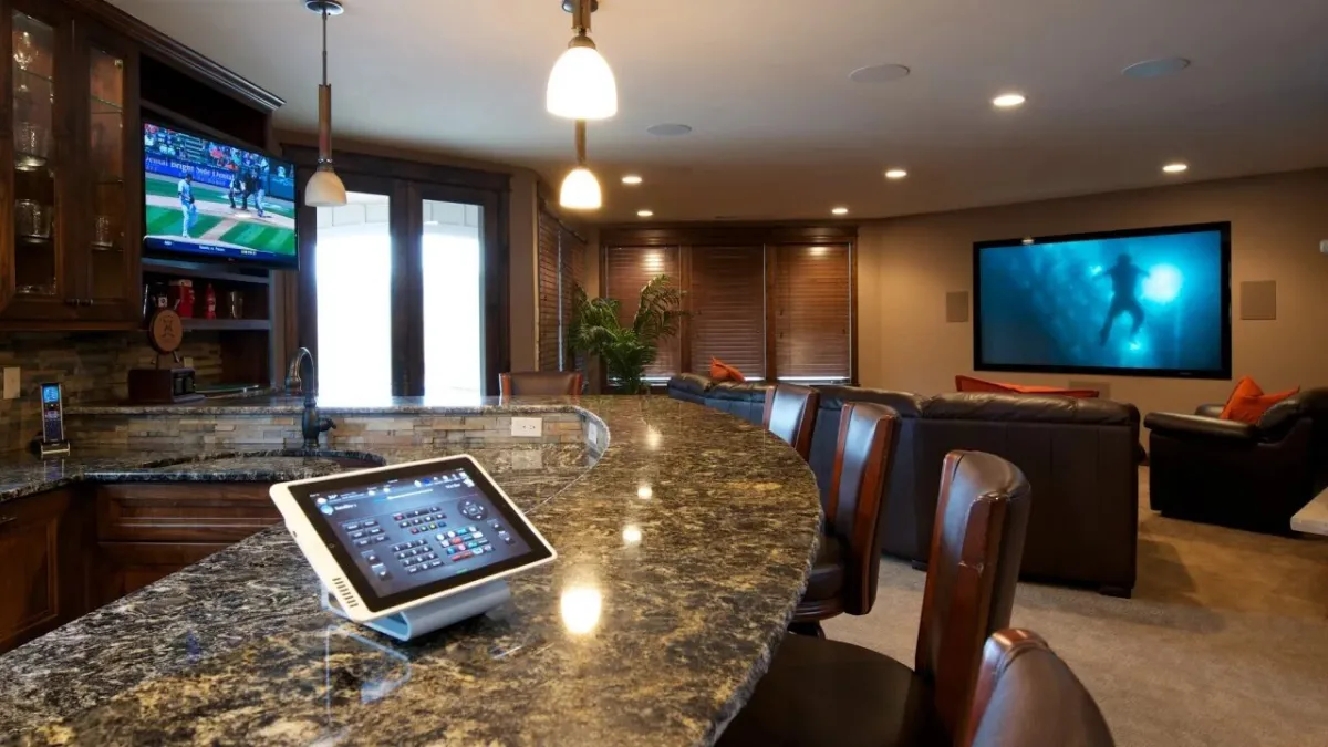 Modern home entertainment bar with granite countertop, leather chairs, and multiple large flat-screen TVs in a cozy room.