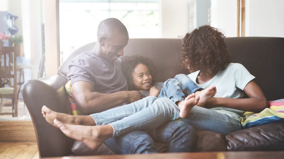 a man and woman sitting on a couch with a child