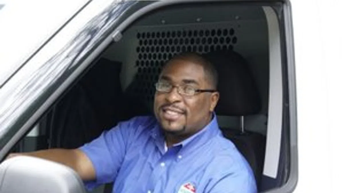 Ackerman Security man in blue uniform driving a white service van with company logo on shirt