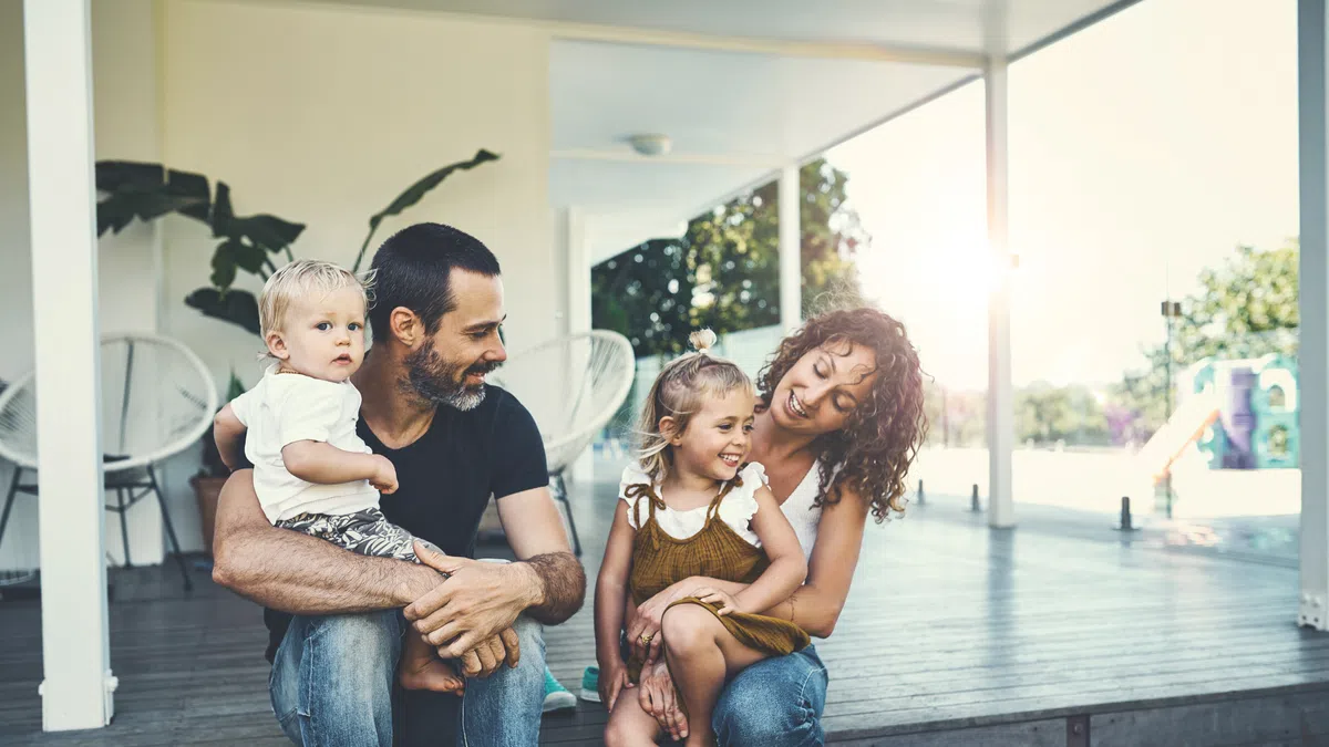 A happy family of four enjoying quality time together on a sunny porch.