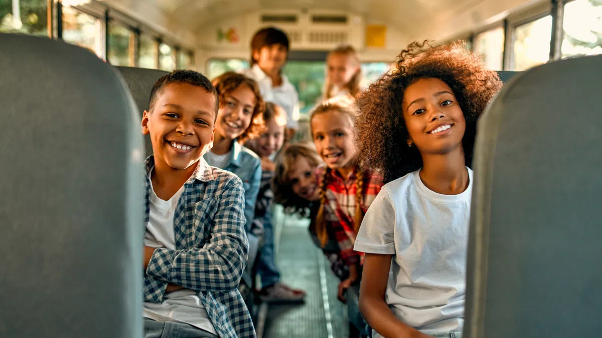 Happy diverse children smiling together on a school bus, showcasing friendship and joy.