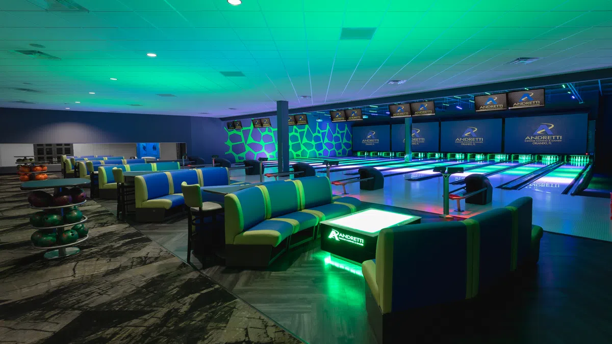 Modern bowling alley interior with vibrant green lighting and sleek seating area.