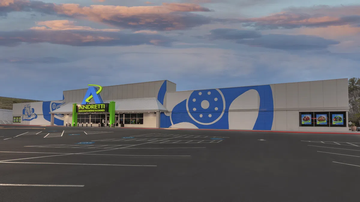 Andretti Indoor Karting and Games building exterior at sunset with large blue racing-themed mural and empty parking lot.