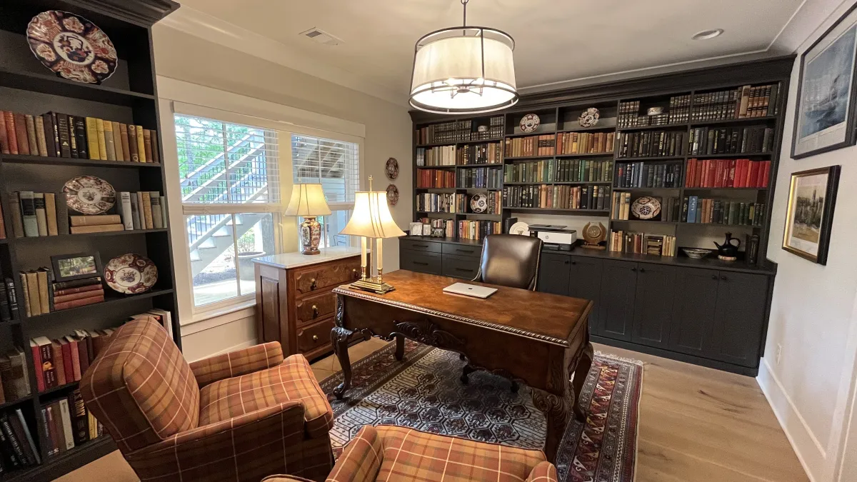 a living room with a desk and bookshelves