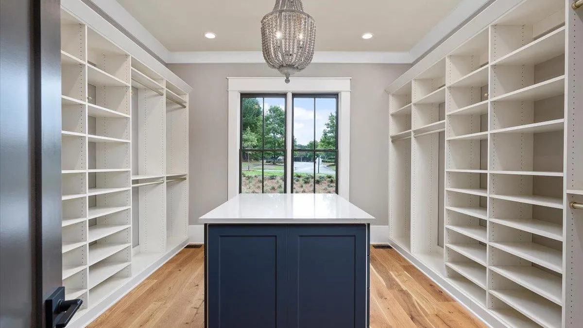 a closet with white shelves and a white island