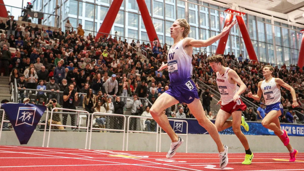 a group of people running on a track with a crowd watching