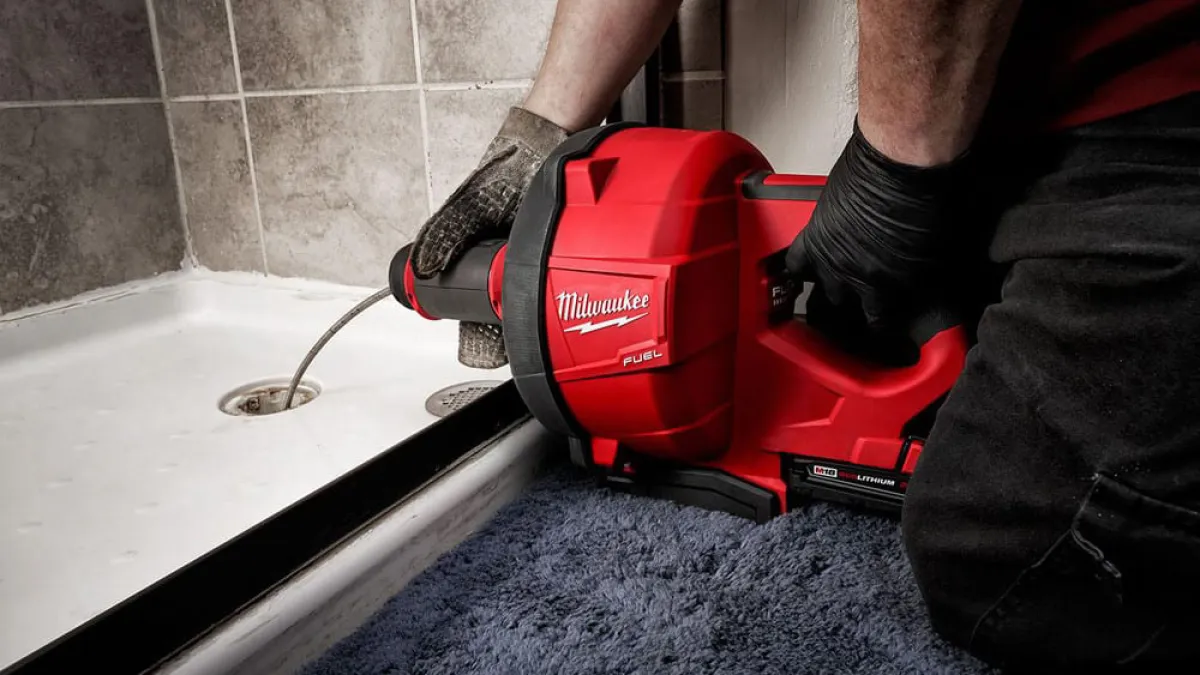 A plumber using a heavy-duty drain snake to clear a shower drain in Dunwoody.