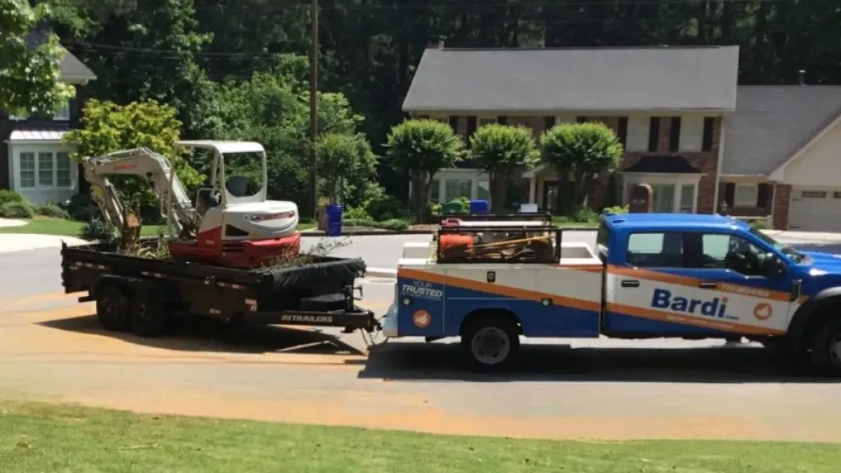 A Bardi branded sewer repair truck towing an excavator in a neighborhood near Dunwoody, GA.