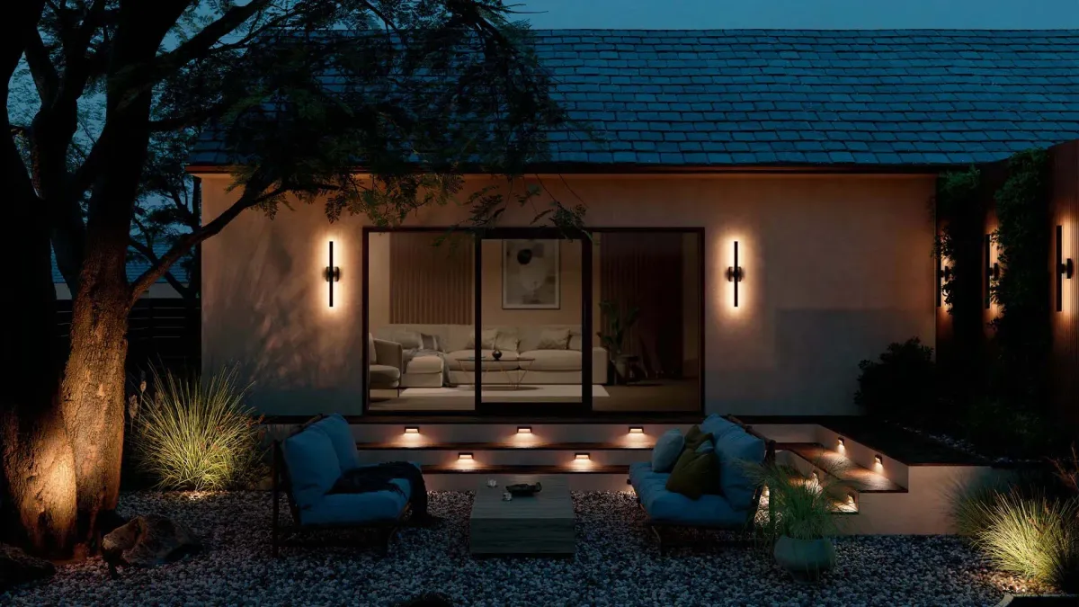 Modern home exterior at night with cozy seating, warm lighting, and landscaped garden elements.