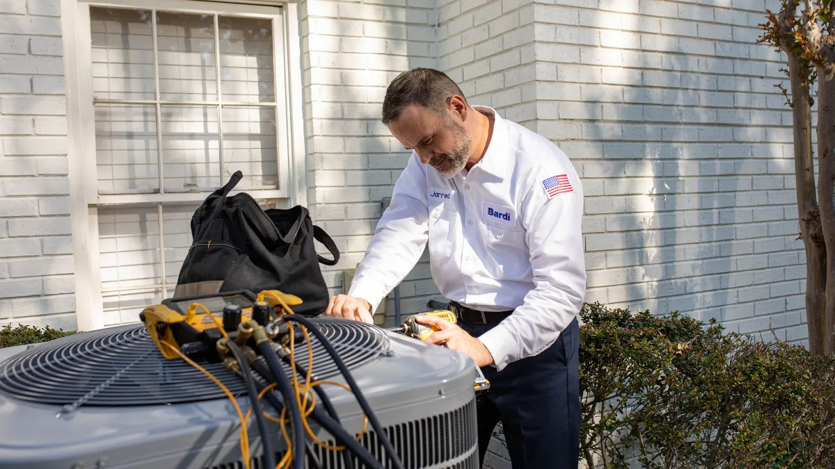 Bardi technician performing maintenance on a residential air conditioning unit.