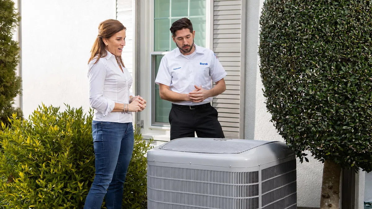 Homeowner consulting with technician about new energy-efficient HVAC unit installation.