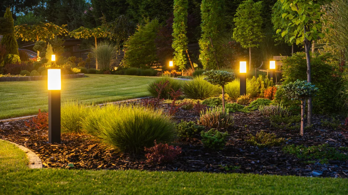 Landscape lighting installation in Atlanta with LED pathway lights illuminating garden beds and lawn at night