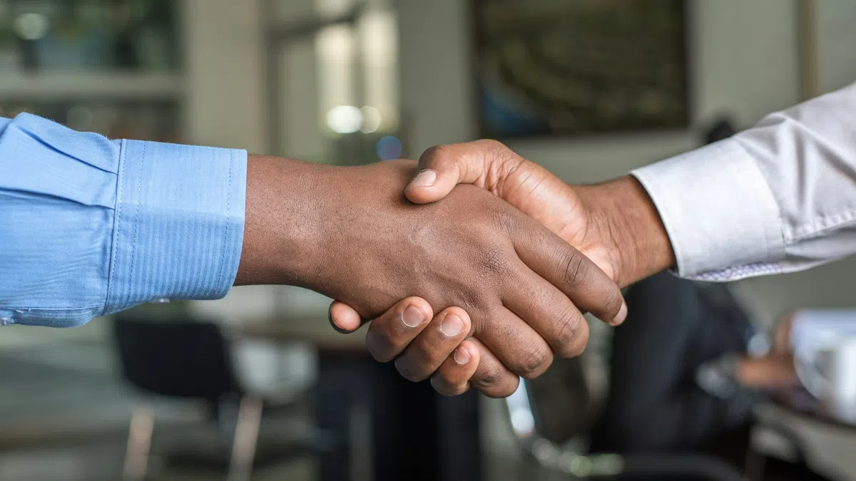 Close-up of two people shaking hands in a professional office setting symbolizing agreement and partnership.