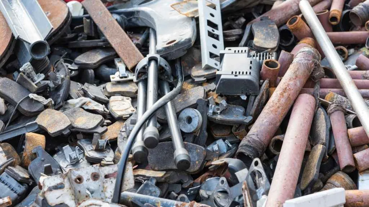 Pile of assorted rusty metal scrap and machine parts in a cluttered junkyard setting