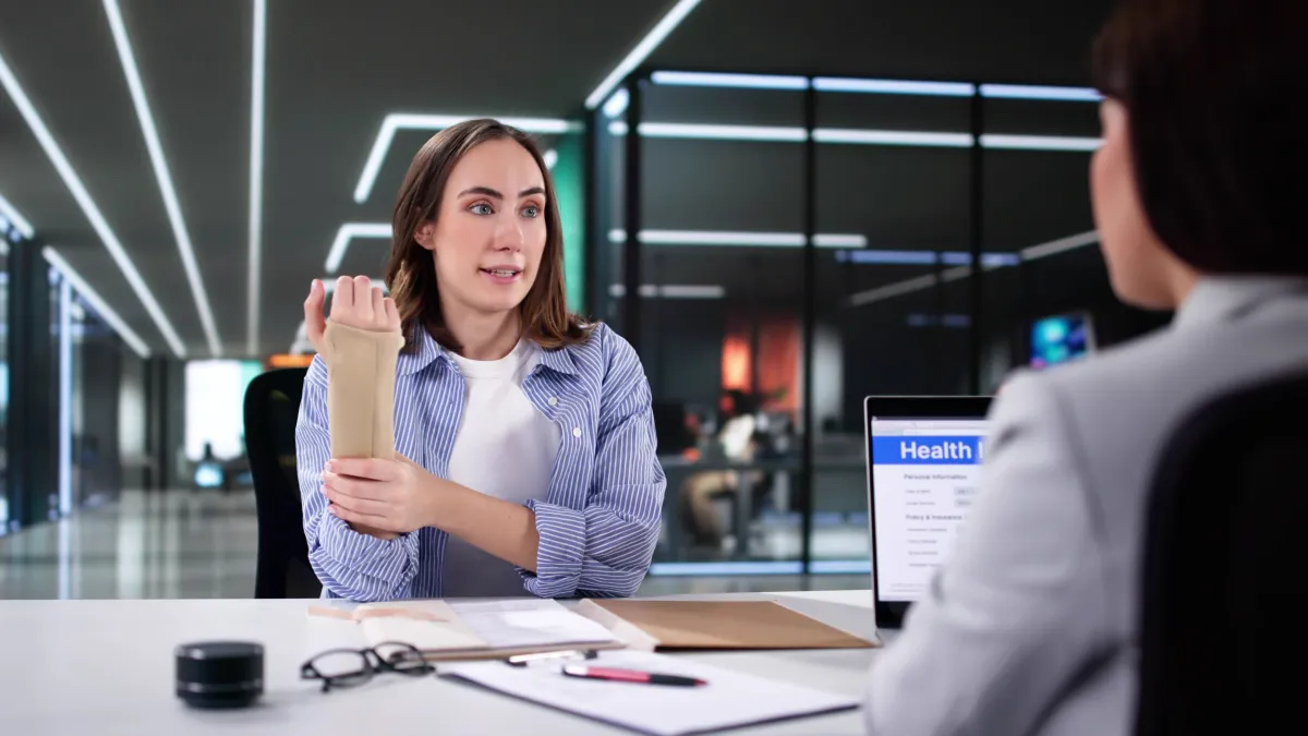 Woman with wrist injury wearing a brace consulting a healthcare professional in a modern office setting.