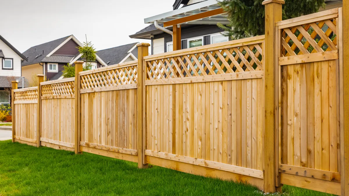A well-maintained wooden fence with lattice design, enhancing a home's outdoor aesthetic in a suburban neighborhood.