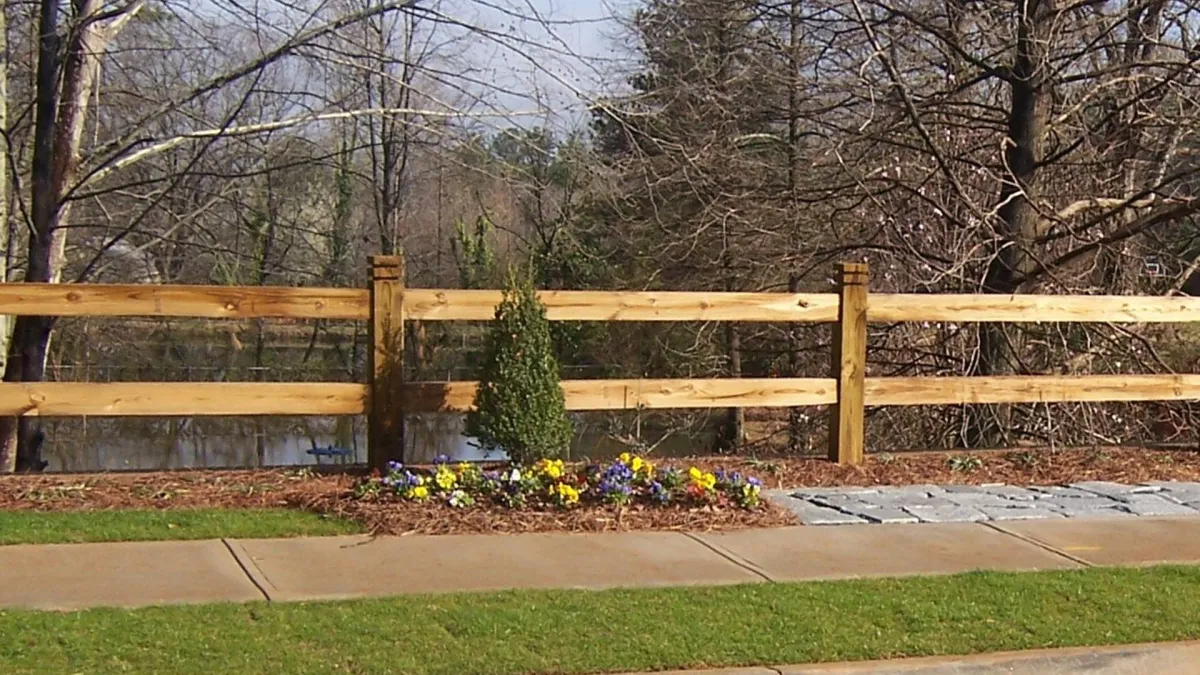 a wooden fence with flowers and grass