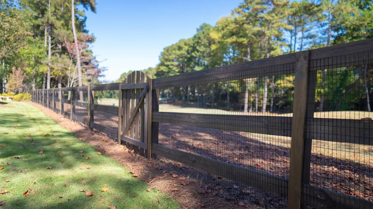 a fenced in area with a metal gate and trees in the background