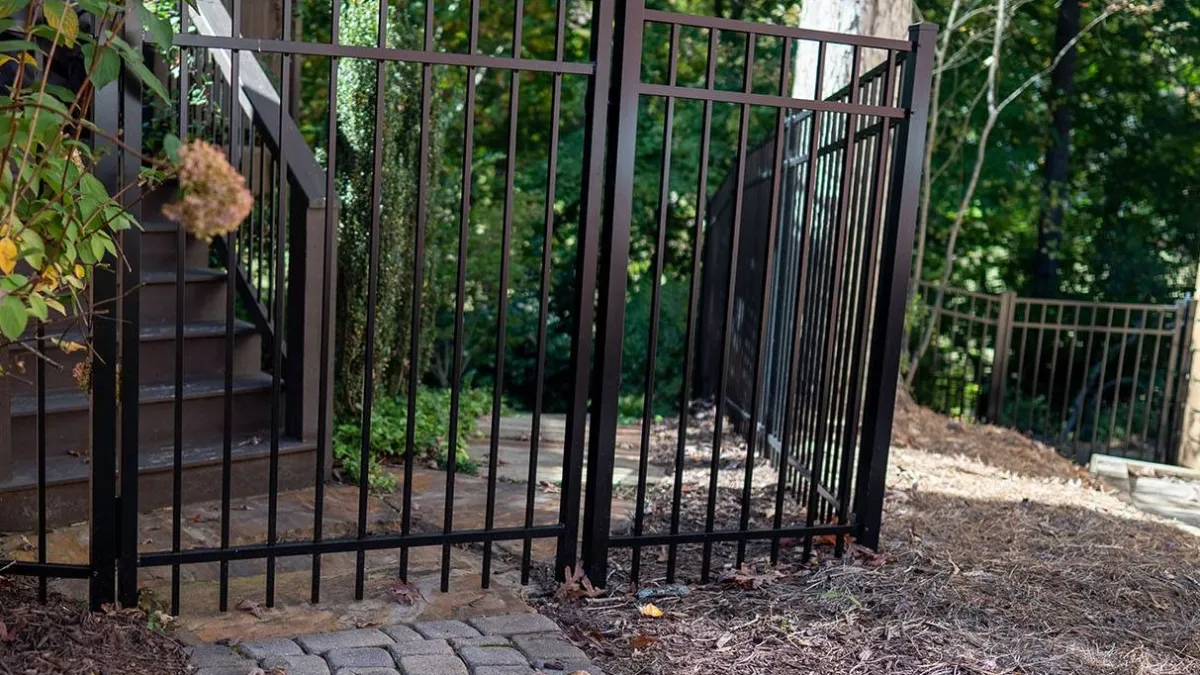 a gated yard with a metal gate and a brick wall